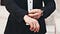 A man in a suit wearing an expensive watch adjusts his sleeves
