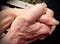 Young woman’s hand holding her father’s bigger, ageing hand