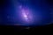 A purple galaxy in a dark blue sky full of stars.