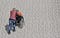 A woman pushes an elderly woman in a wheelchair across a sidewalk.