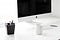 An iMac sitting on the desk with a stationery set and coffee mug.