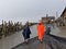 Two intrepid researchers walking through a small fishing village, with thatch huts and wooden fencing, in a torrential downpour.