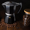 A black Moka pot coffee maker around coffee beans in a jar.