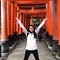 Tiffany standing with her arms up in front of a tunnel made up of red gates.