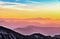 Man standing on top of mountain with colorful sunset behind.