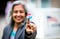 A gray-haired woman holds up a sticker that reads, “I voted.”