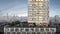 Architectural rendering shows the exterior of a tall timber building. A city skyline is in the background.