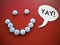 Birth control pills arranged in a smiley face with a speech bubble saying “yay!”