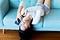 Teenage girl laying down upside down on a couch using her smartphone