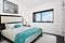white hotel room w/ large window, carpet, and turquoise accents on bedding with a black&white cityscape artwork above the bed