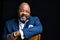 Composer Jonathan Bailey Holland in blue suit and glasses looks directly into the camera