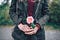 Woman in a leather jacket holding a pink rose in both of her hands