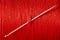 A needle stuck through a wall of red thread.