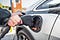 A hand plugging an electric car in to charge.