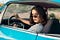 A young woman with sunglasses in a car, looking annoyed