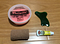 Rehab toolkit laying on ground: Theraputty, my graston tool, 3inch coban tape, and lotion for massage