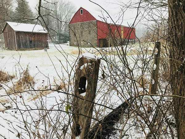 An old barn with red siding seen off in the distance in the countryside.