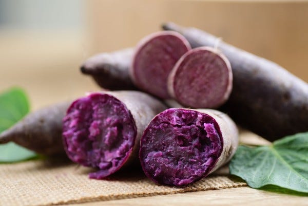 Shows the inside of a sliced purple yam tuber in a rich lavender color