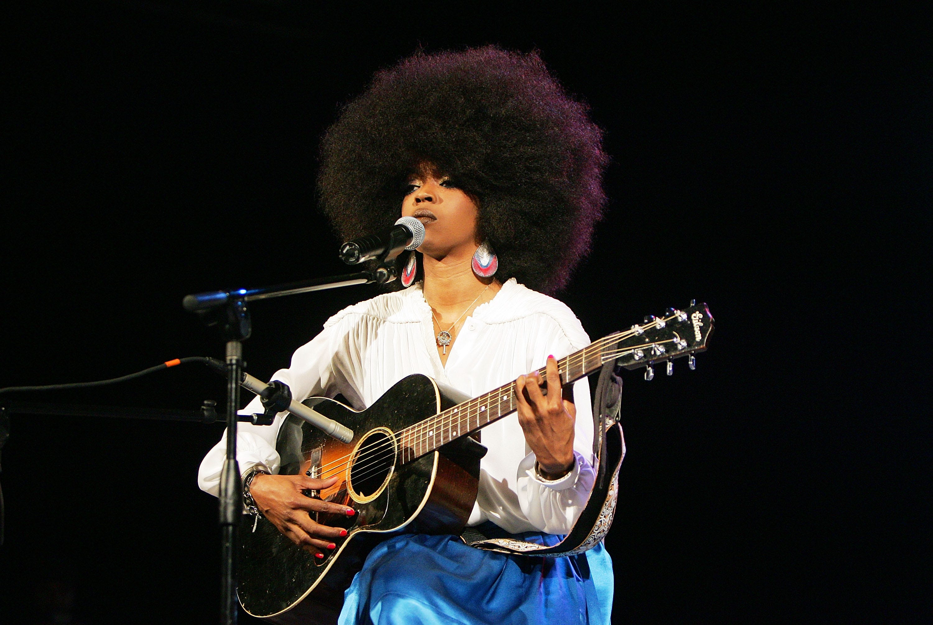 La artista Lauryn Hill tocando la guitarra en un concierto