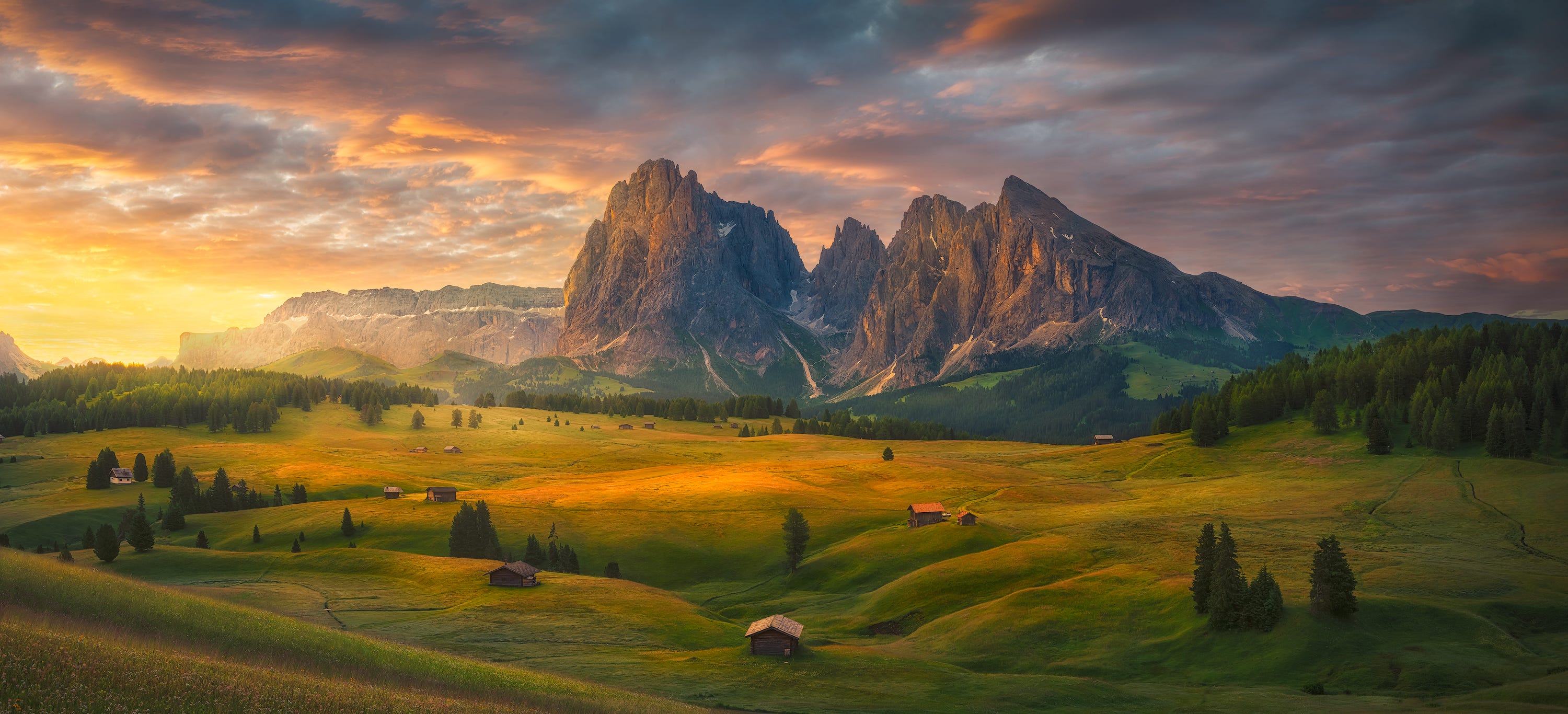 The sunrises over a valley in Italy, backed by a beautiful mountain and dotted with charming, small houses