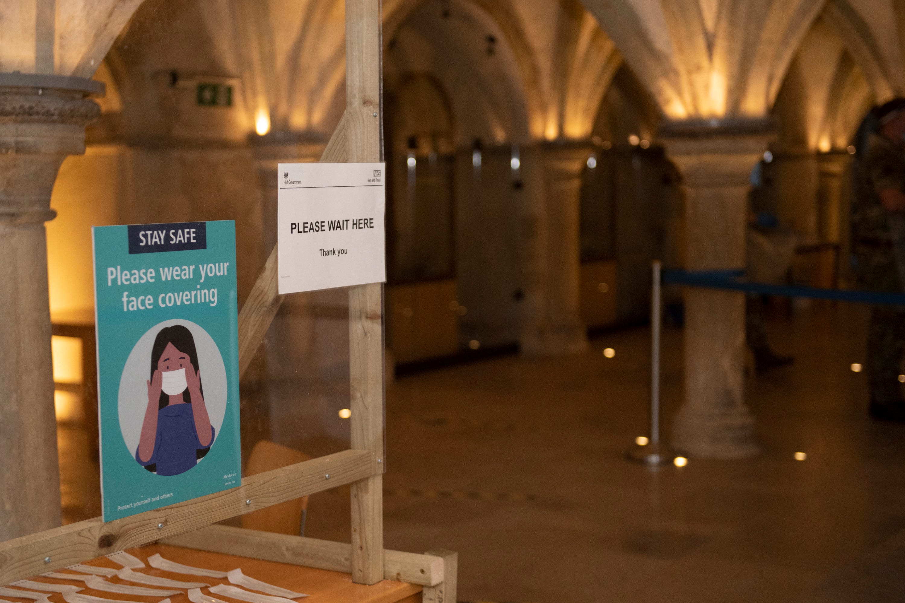 A sign reading “please wear your face covering” greets guests in a pillared hallway