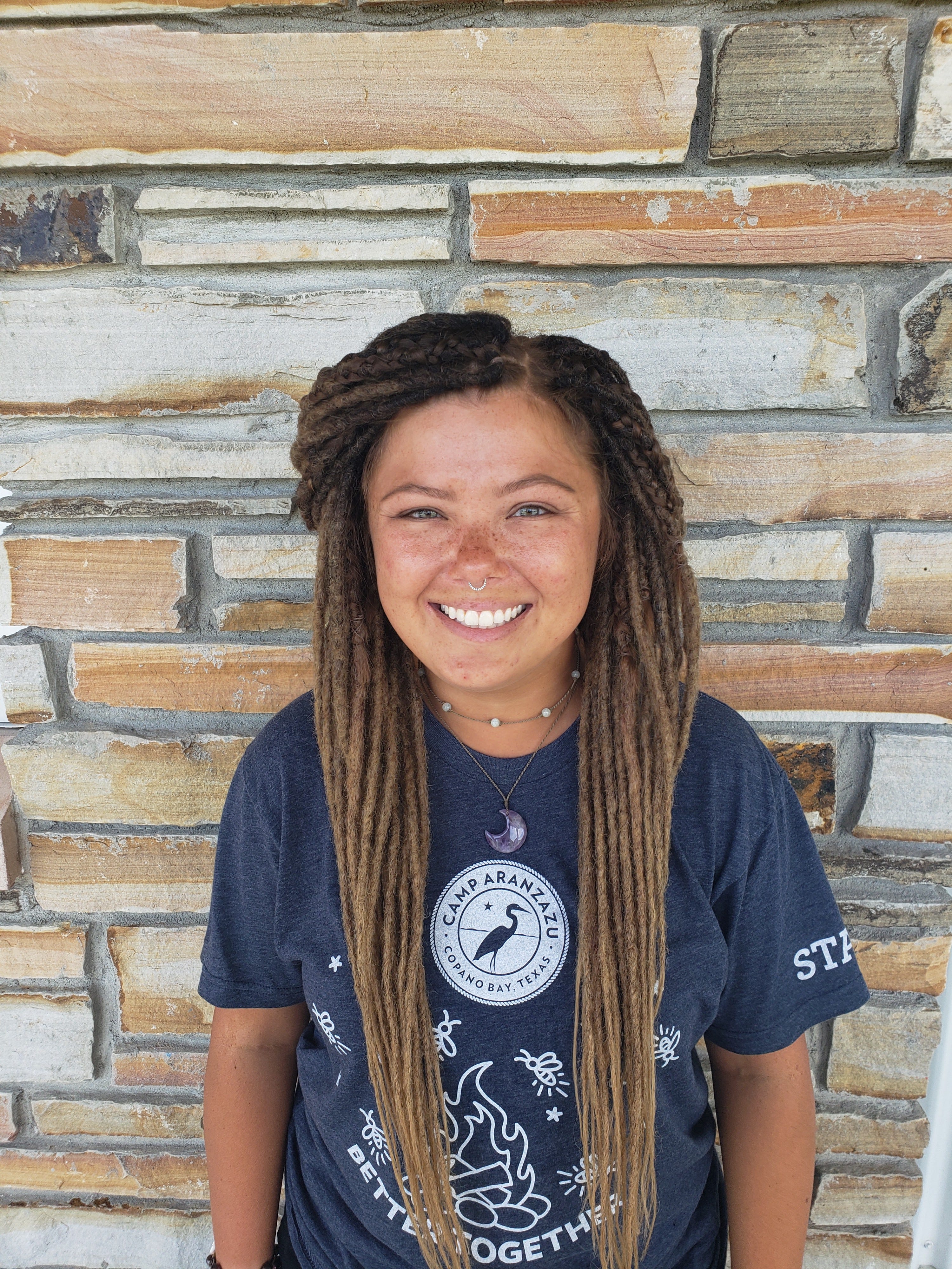 Activity leader misty smiles and stands against brick wall