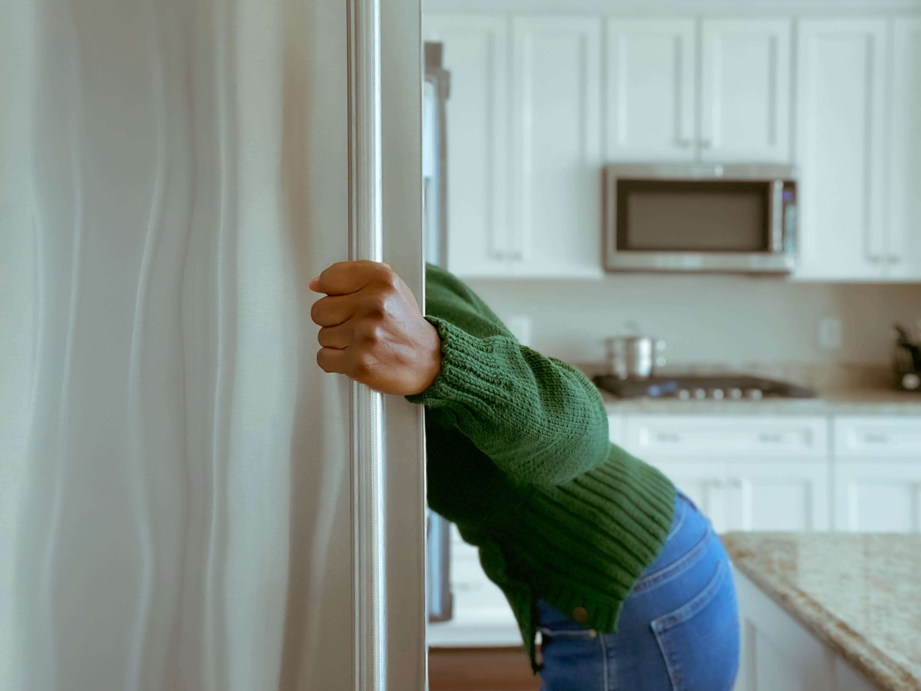 Woman looking into fridge, holding door open.
