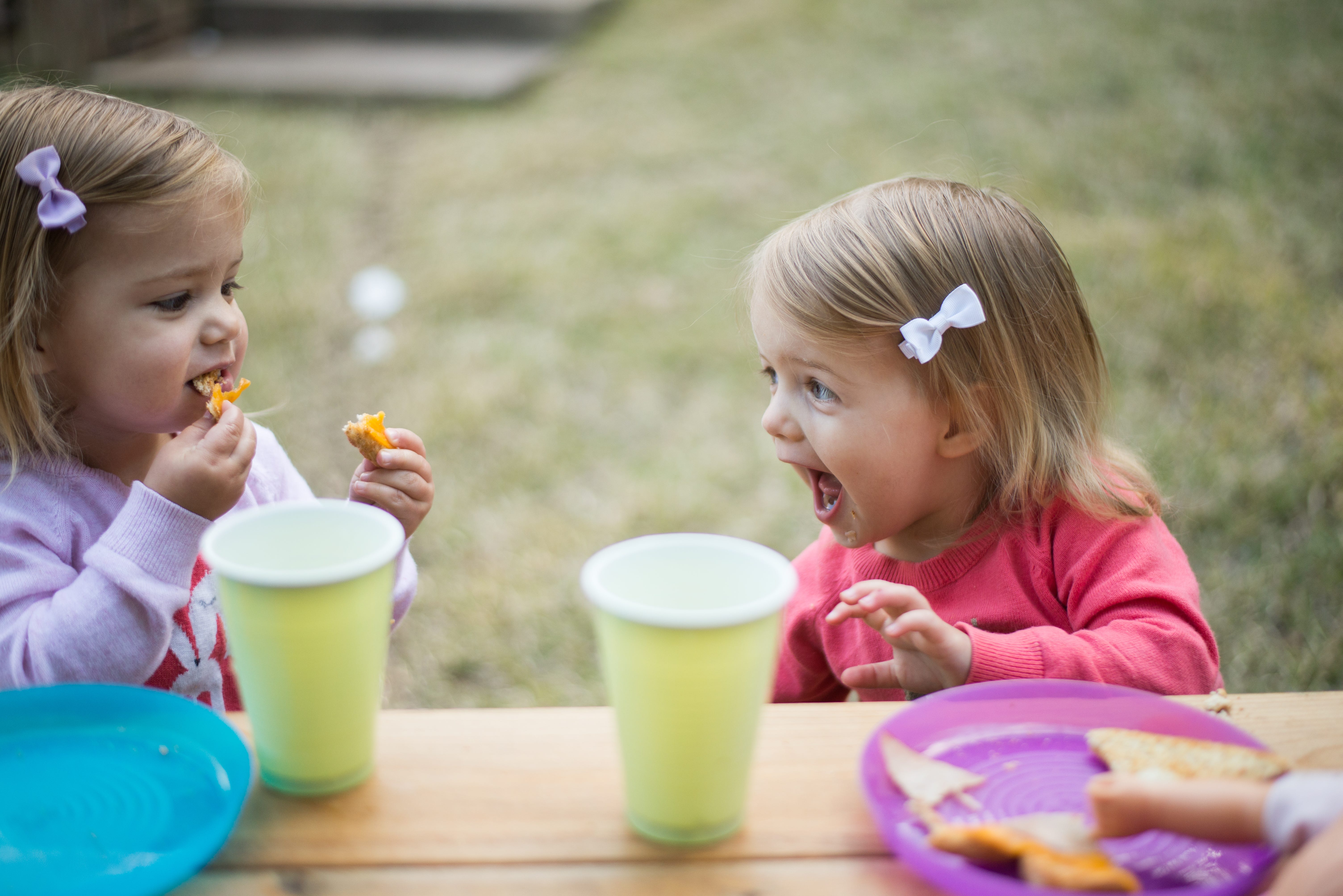 Two small children sharing food and talking in amazement