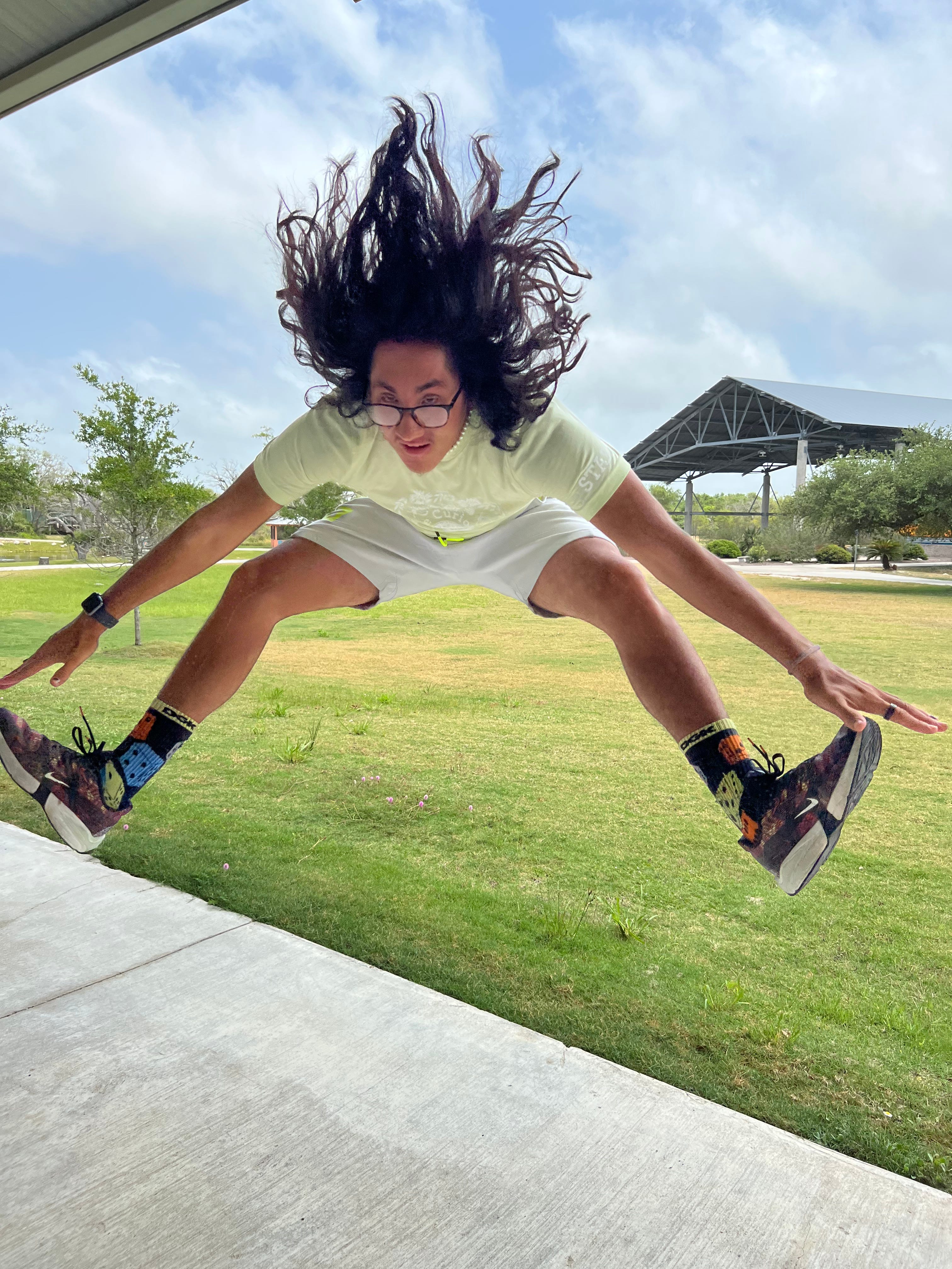 Activity leader arnold jumps up in air and touches his toes in a straddle in front of the pavilion