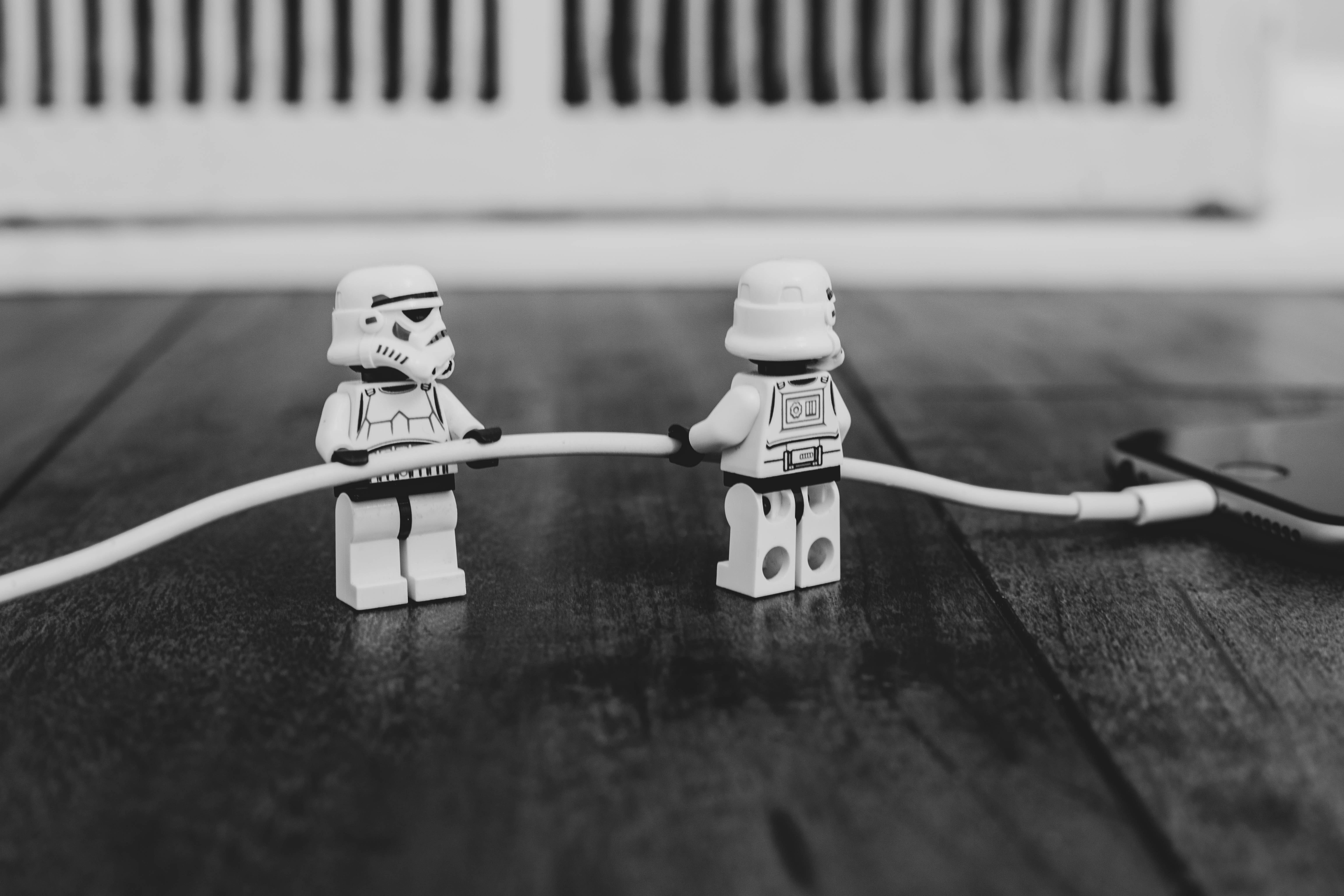 A photo of 2 Stormtroopers Lego figurines holding the wire of a charging phone — Photo by Will Porada on Unsplash