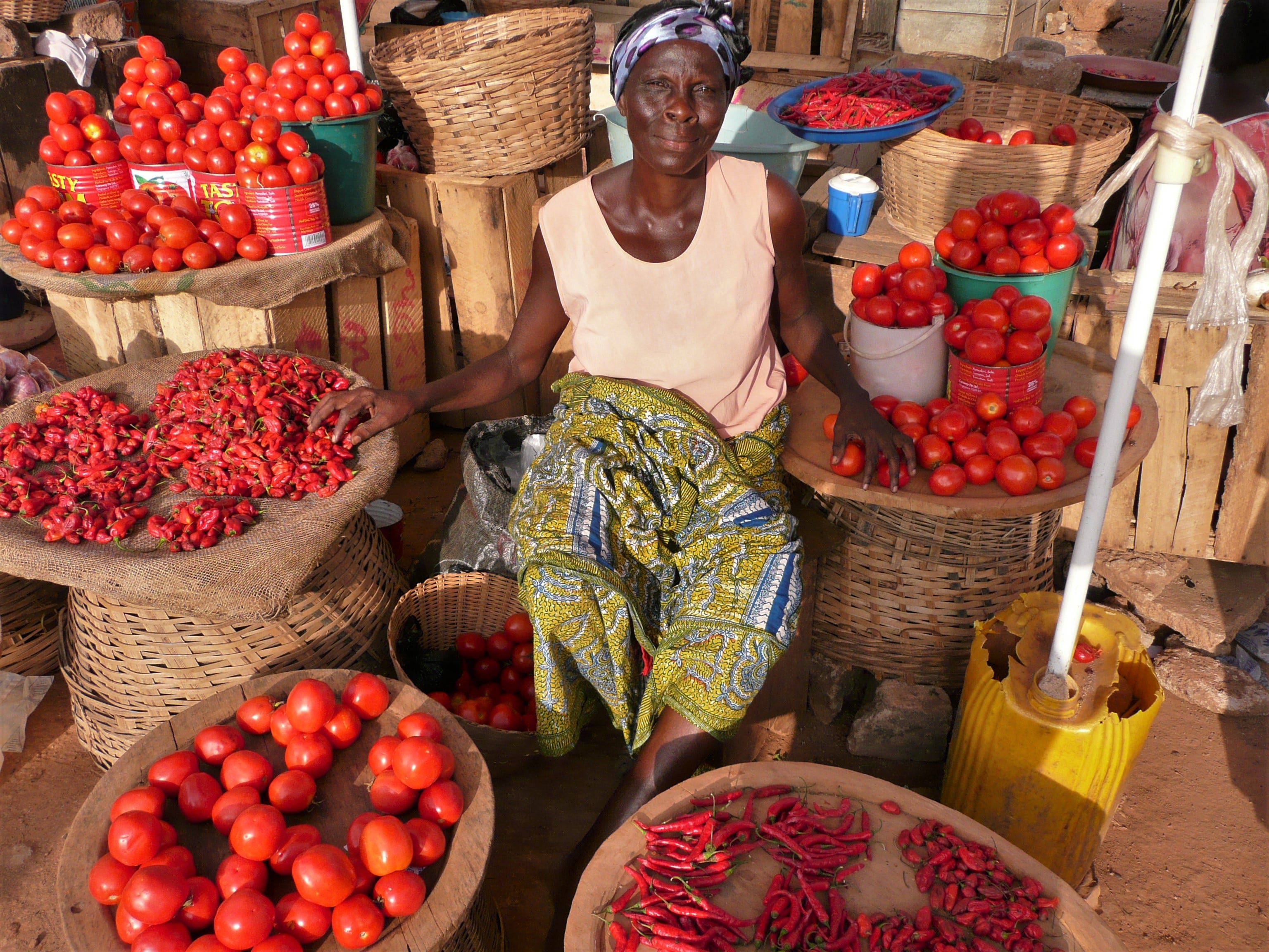 Marktverkäuferin umrandet von Tomaten und Chilischoten