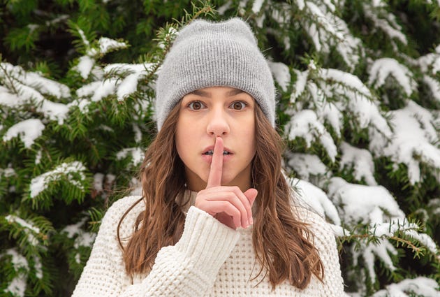 Woman with index finger over mouth