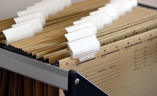 A photo of dozens of manila files cramed inside a drawer. Photo by Ulrike Mai via Pixabay