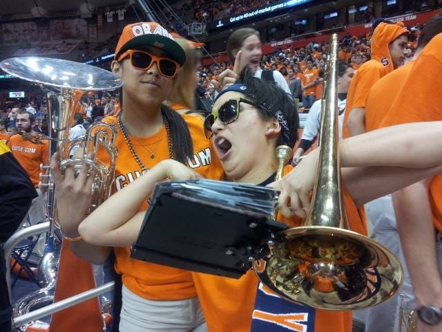 Erin dancing with others in pep band, while she holds a trombone