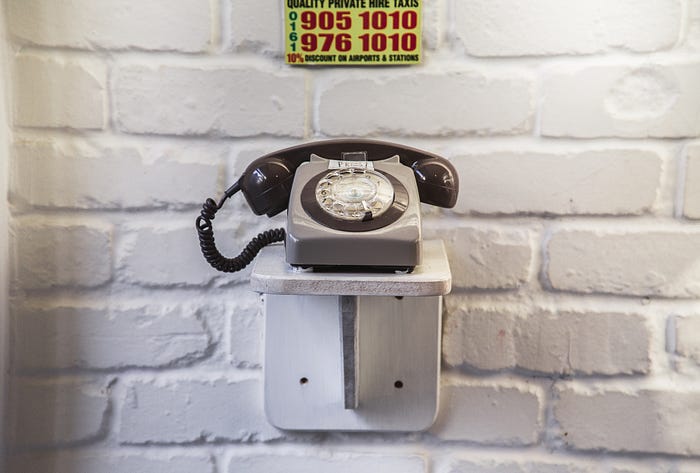 an old telephone on a white brick wall