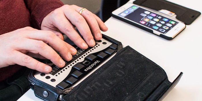 A close up of a person’s hands using a Braille display.