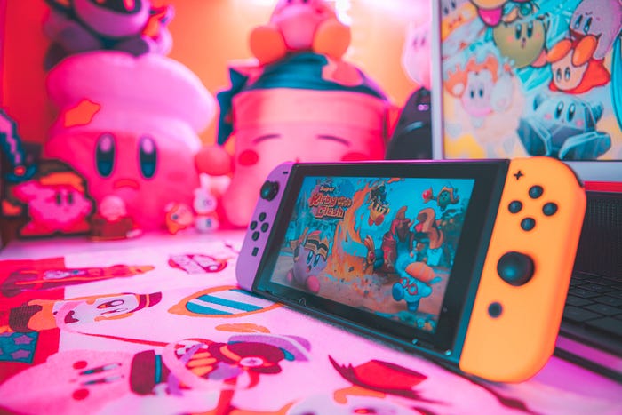 A Nintendo switch sits in front of Kirby gear
