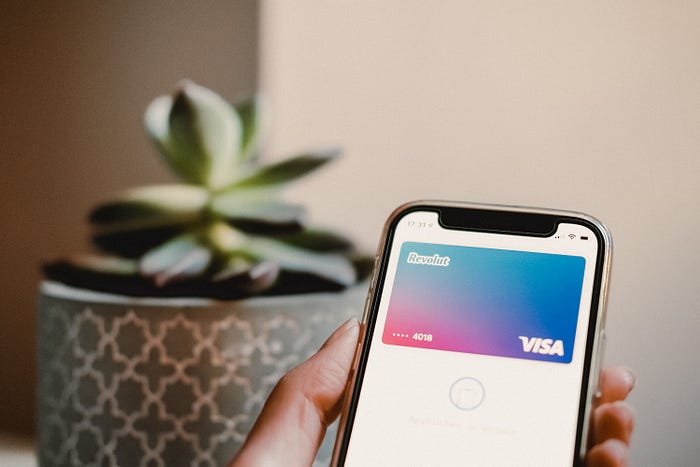 Photo of someone holding an iphone with Revolut digital Visa card displayed