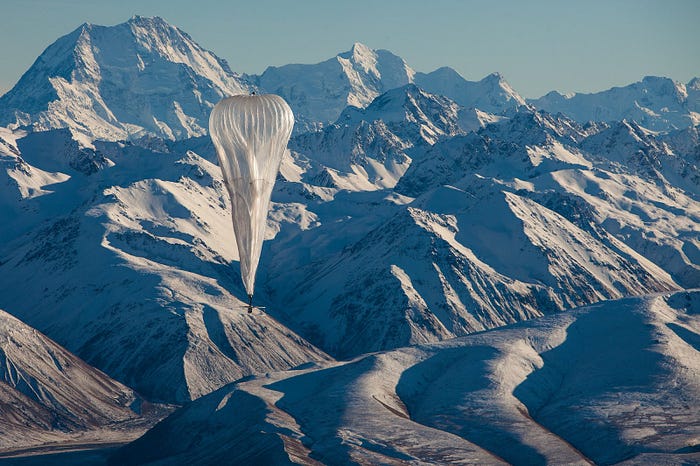 A Loon balloon in the foreground against snow-covered mountains in the background