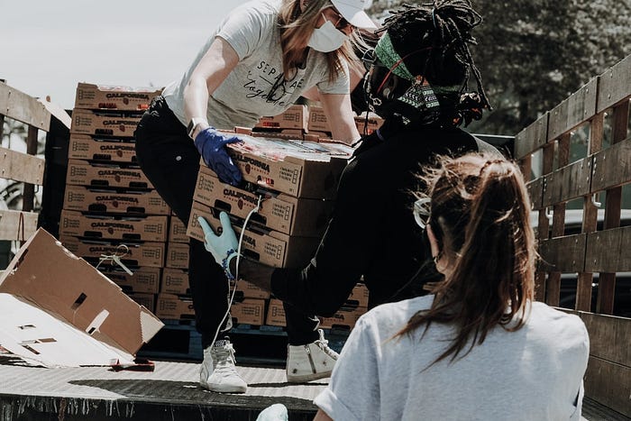 Volunteers move boxes off a truck with their masks on.