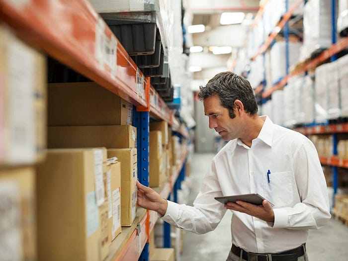 A man looking at boxes in a warehouse.