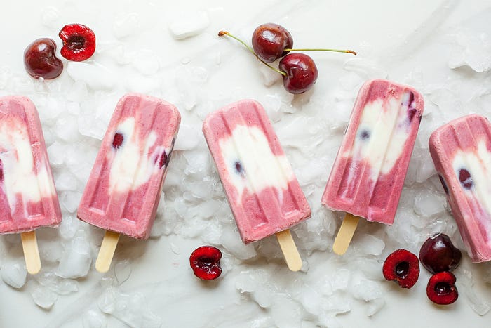 Pink and white popsicles with cherries by the side