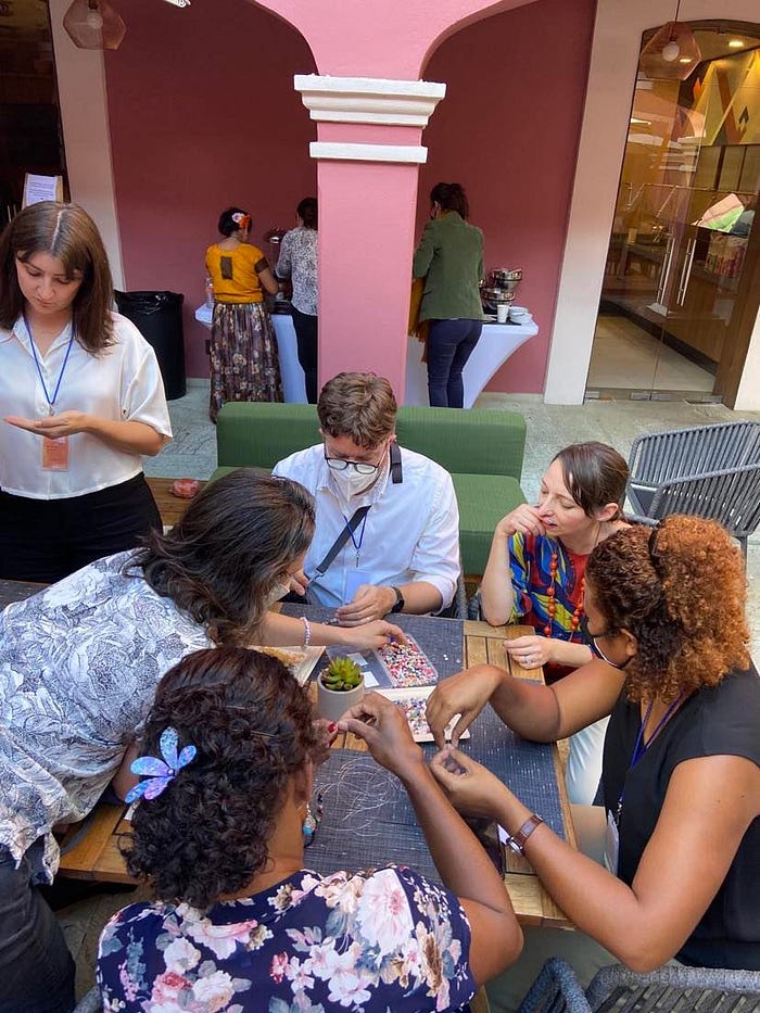 A group of six people sit around a table doing an arts and crafts activity.