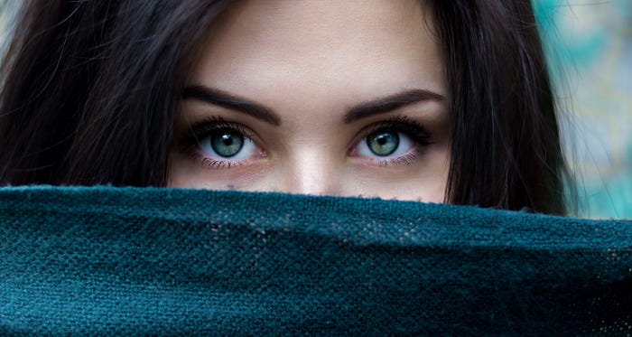 Woman’s eyes looking over a barrier that covers the bottom half of her face