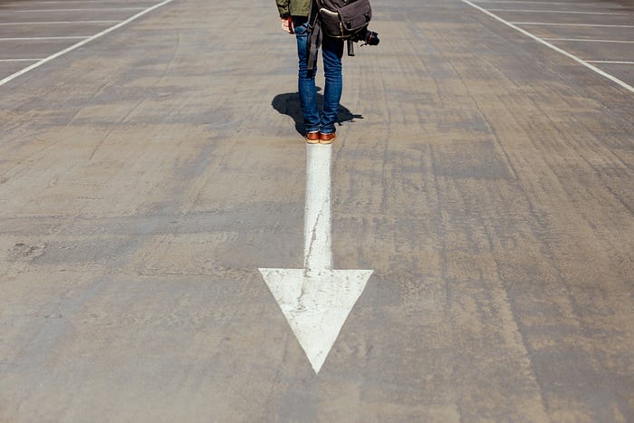 man standing on the street on the end of an arrow