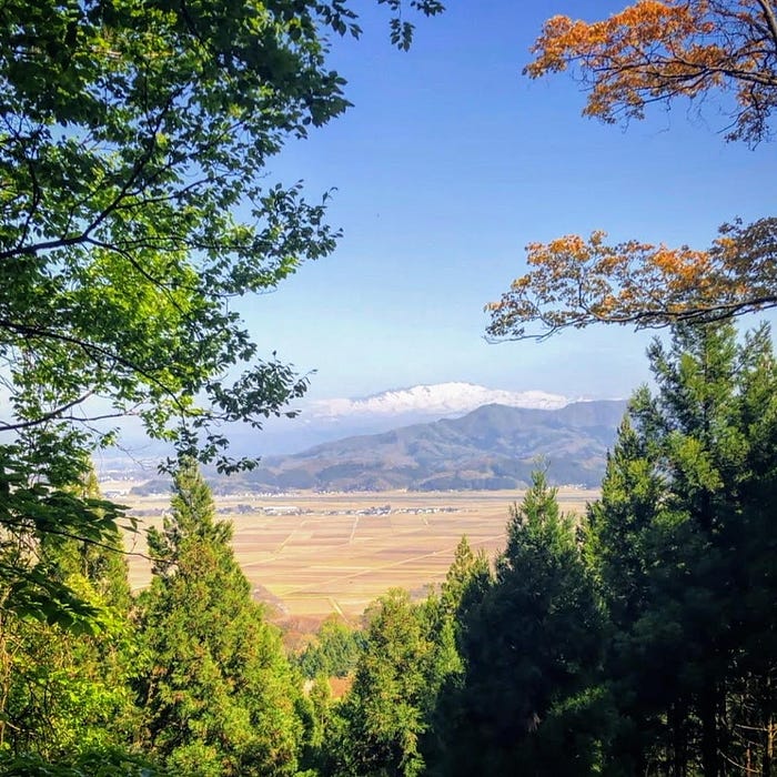 Mt. Gassan covered in snow beyond the rice fields in the distance from the base of Arakura Shrine on Mt. Arakura, one of the 100 Famous Mountains of Yamagata