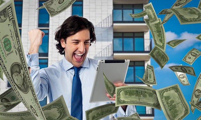 A businessman looks at his tablet as money falls from the sky…much to his excitement.