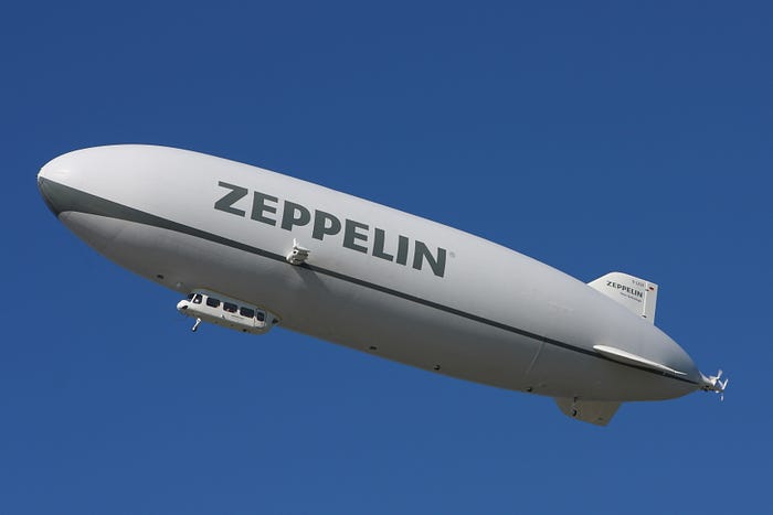 How Are Big Airships Really Making A Comeback Again? — The image of an elegant Modern Zeppelin NT D-LZZF — 2010 (Image from Wikimedia Commons) — The white airship floats majestically against a clean cloudless blue sky.