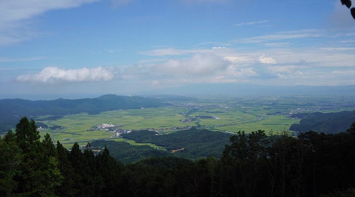 A view over the rice fields of the Shonai Plains and Mt. Chokai shrouded in cloud taken from the summit of Mt. Kumanonagamine, one of the 100 Famous Mountains of Yamagata in Tohoku, north Japan.