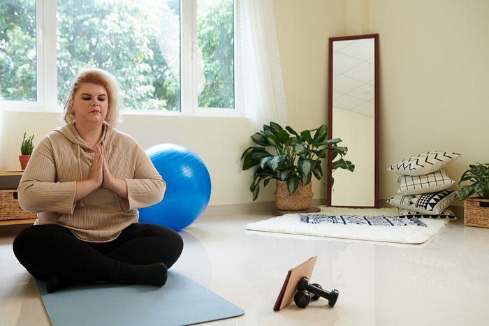 Plus size woman practicing yoga at home to improve overall physical health